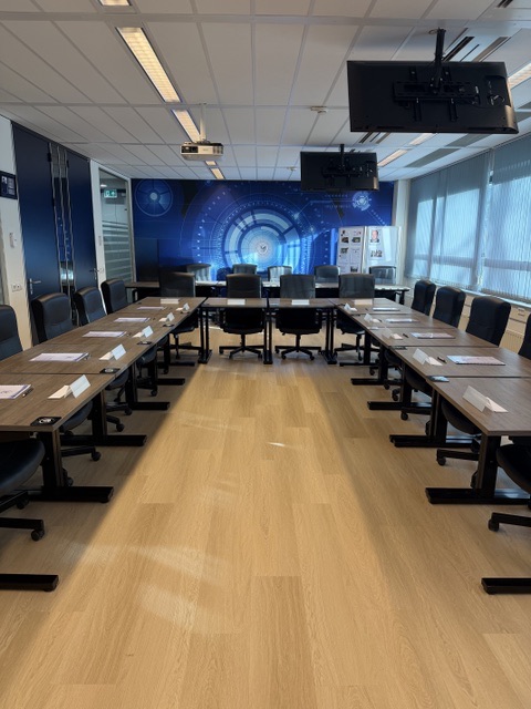 Classroom in U-shape layout with conference tables, projector and screen